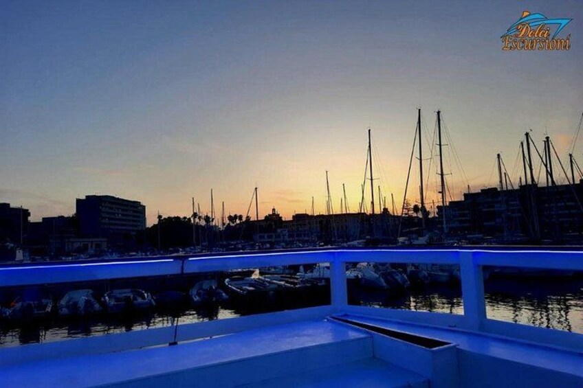 Een jachthaven in de schemering met aangemeerde boten en een stadsachtergrond. 3