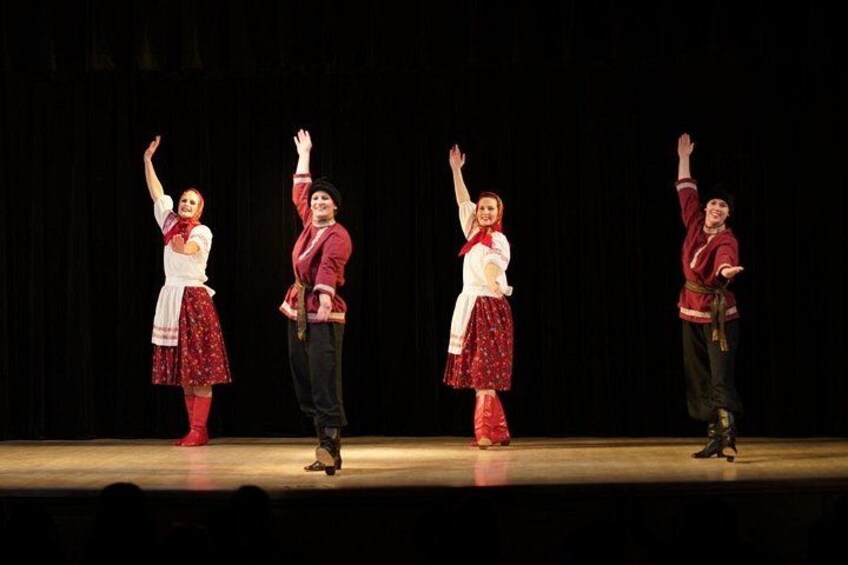 Four people in traditional costumes performing on a stage. 5