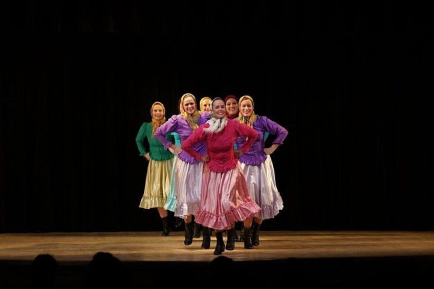 A group of people in colorful traditional costumes on a stage. 4