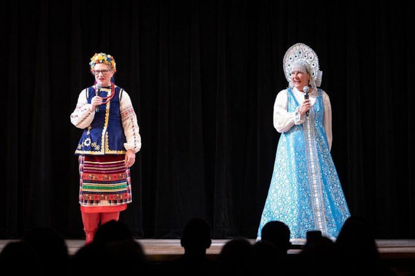 Two individuals on stage in traditional costumes. 5