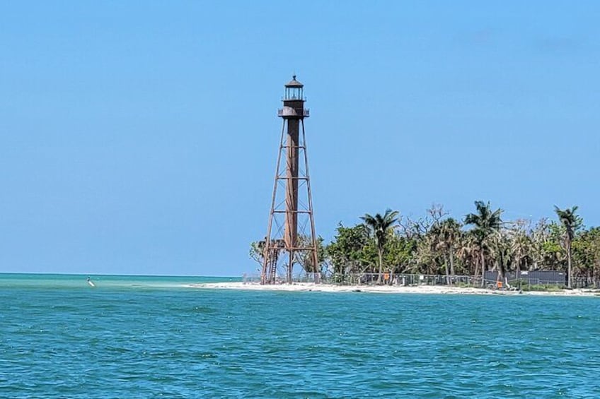 Un faro en una playa con aguas azules cristalinas y palmeras. 2