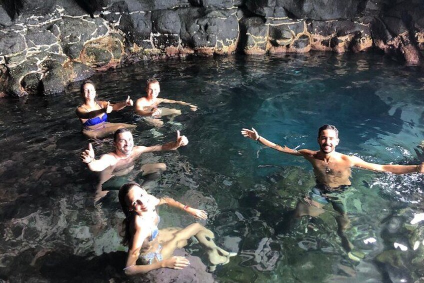People swimming in a natural pool surrounded by rocky terrain. 4