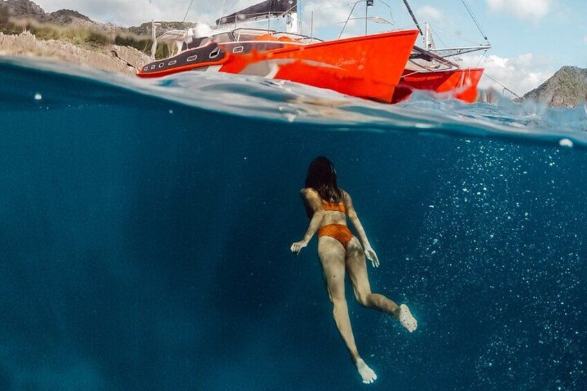 A person swimming underwater with a boat in the background. 1