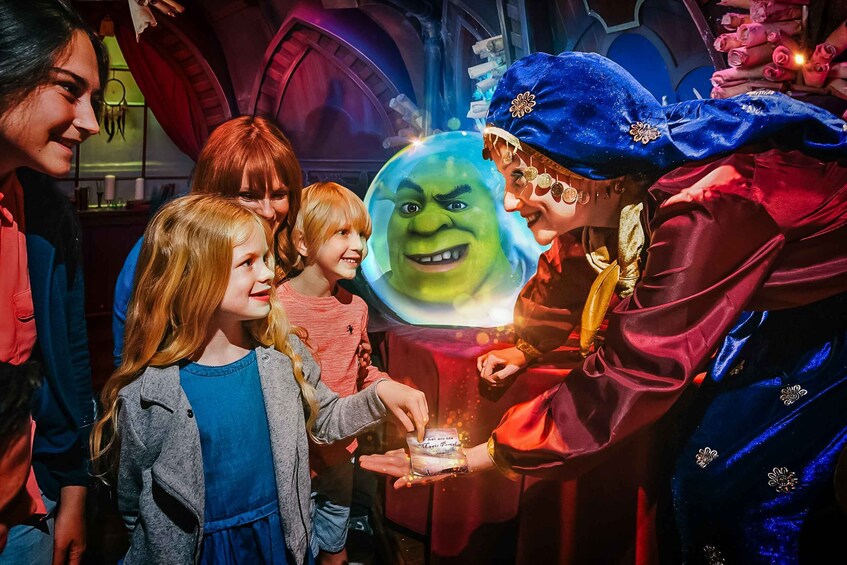 A person in a blue and gold costume interacting with children in a themed environment. 1
