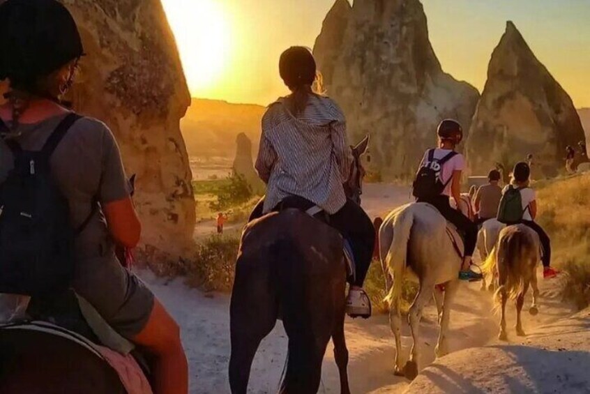 People riding horses on a trail with large rock formations in the background. 5
