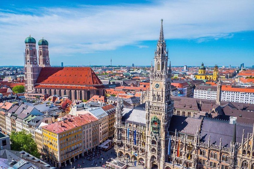 A cityscape with a prominent church, a tall clock tower, and a red-roofed building. 2
