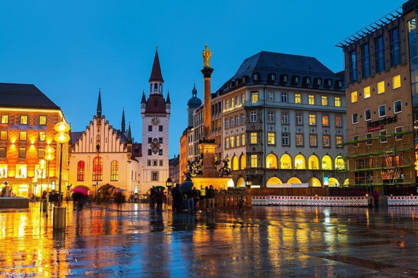 A historic European square with illuminated buildings and a reflective water surface. 4