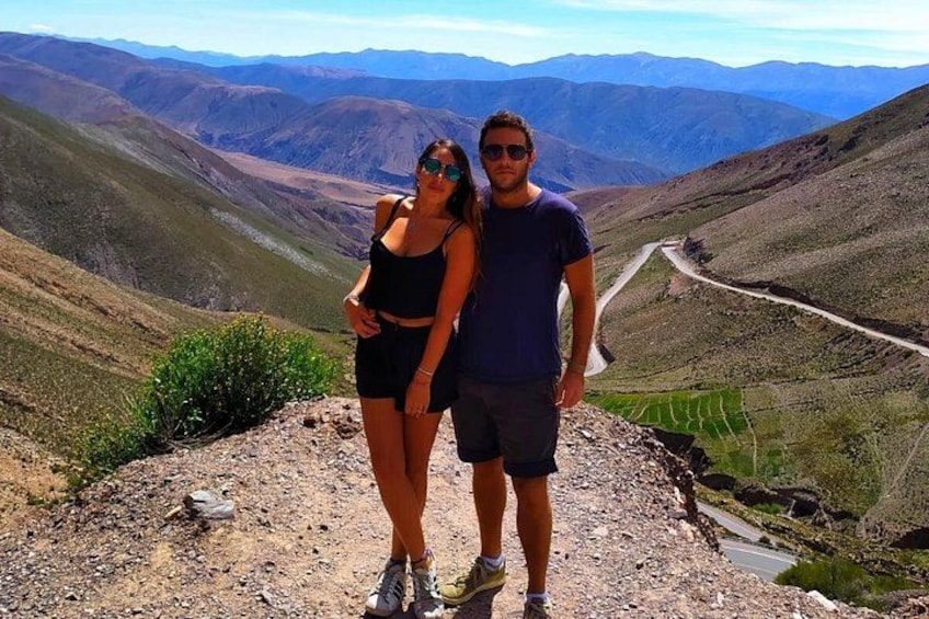 Un couple se tient sur une crête montagneuse, avec une vallée et une route en arrière-plan. 5