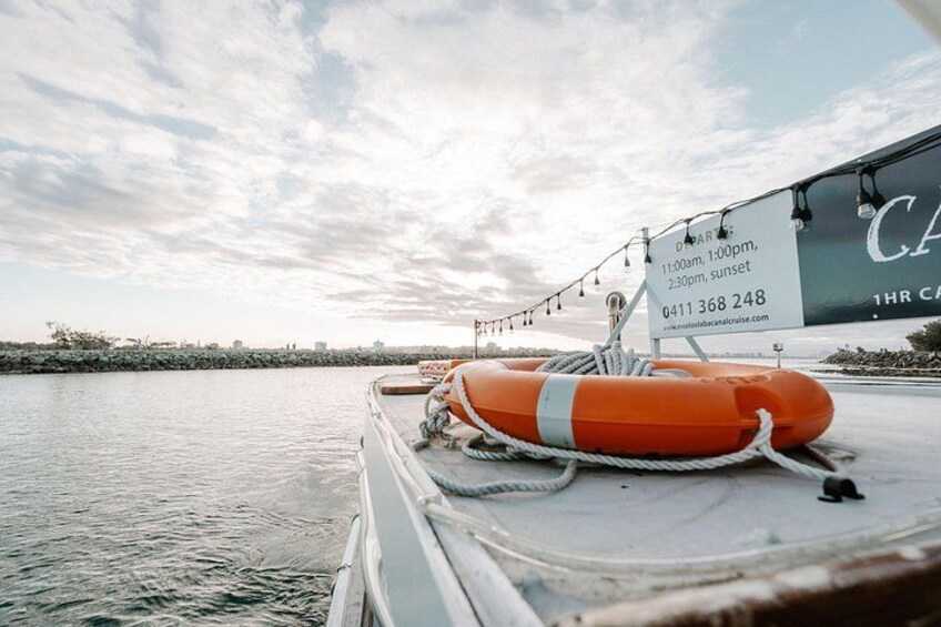 Eine Rettungsboje auf einem Boot, ein Schild mit Kontaktinformationen und ein bewölkter Himmel. 4
