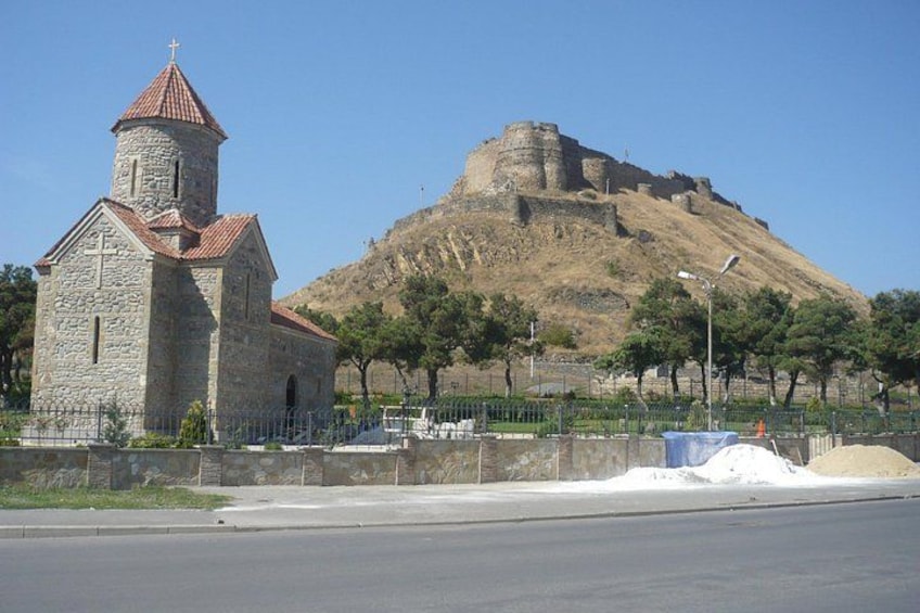 Eine Kirche mit Kirchturm und einer Festung auf einem Hügel. 4