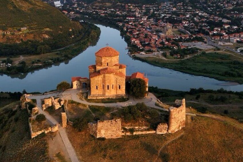 Eine historische Kirche mit einer Kuppel, umgeben von Ruinen und einem Fluss. 1