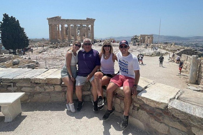 En grupp människor sitter på gamla stentrappor med Parthenon i bakgrunden. 3