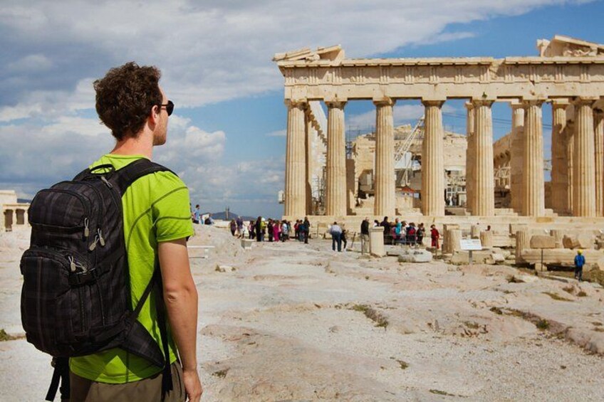 En person med en ryggsäck som står framför Parthenon i Aten. 2