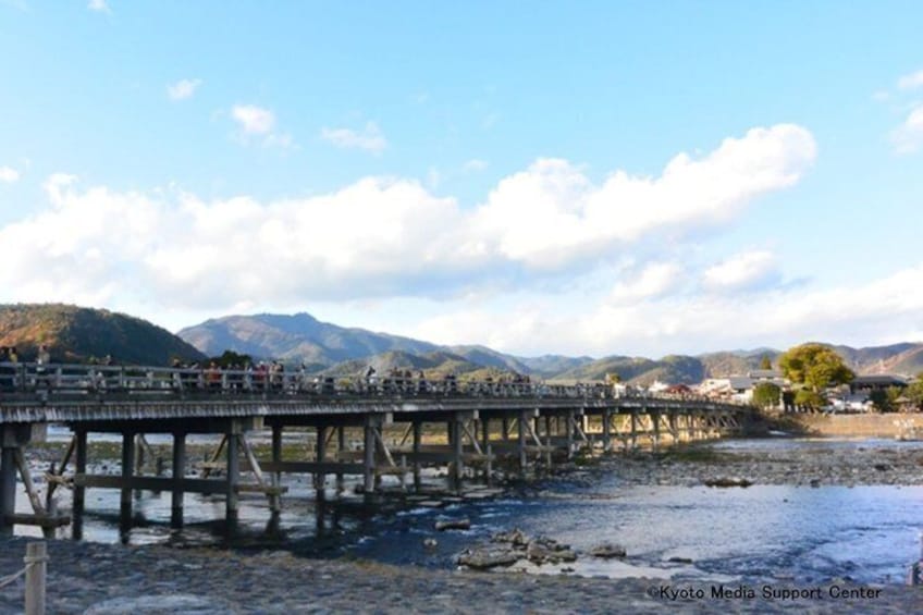 A wooden bridge over a river with mountains in the background. 3