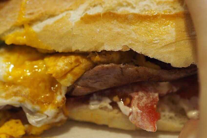 Ein Sandwich mit geschmolzenem Käse, Fleisch und möglicherweise Gemüse. 3