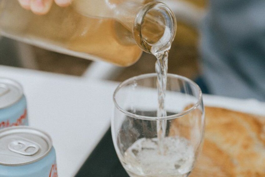 Ein Glas wird mit einer klaren Flüssigkeit, möglicherweise Wasser, gefüllt, im Hintergrund stehen eine Dose und eine Scheibe Brot. 4