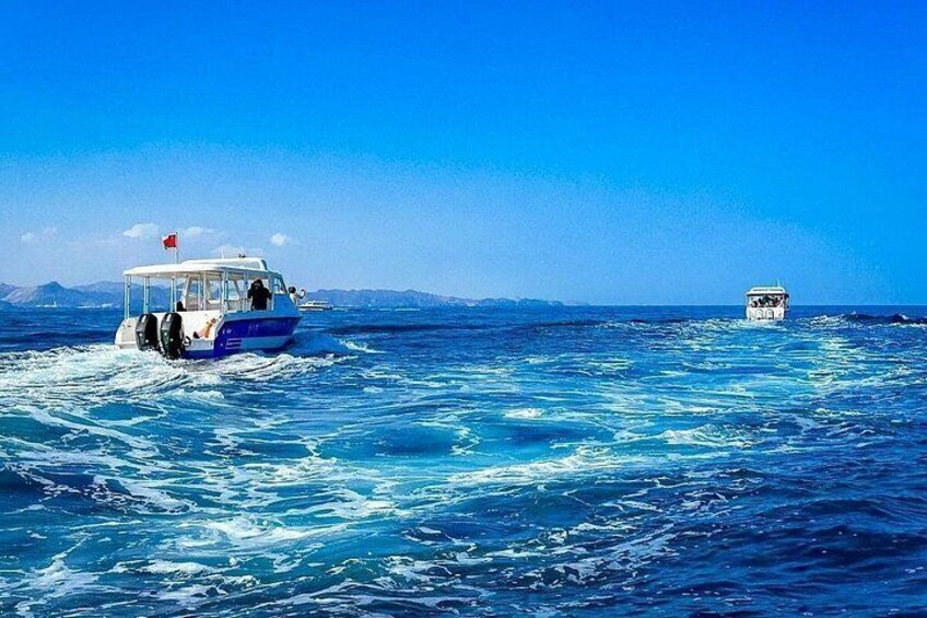 Due imbarcazioni su un oceano blu con onde, un cielo sereno e montagne in lontananza. 2