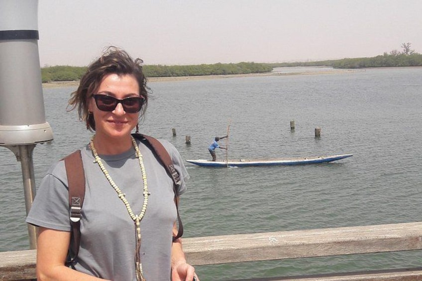 Una persona está de pie junto al agua, con un bote a pedales a lo lejos. 3