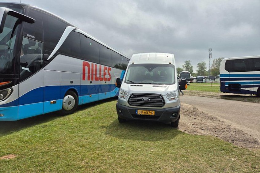 En bus med teksten 'Nilles', en hvid varevogn og en anden bus i baggrunden. 3