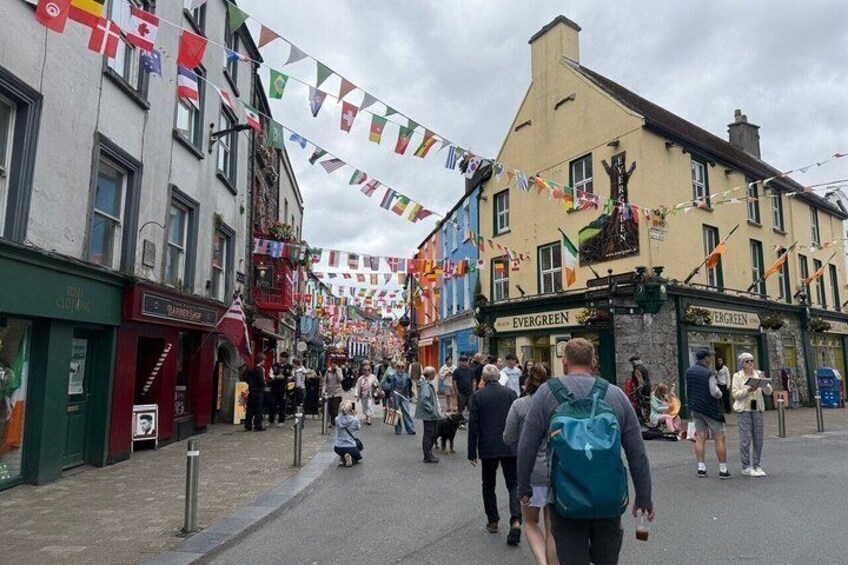 A street with buildings, flags, and people walking. 3
