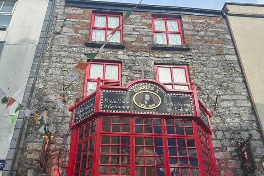 A historic building with a red facade, a sign reading 'Charles's Public House & Restaurant,' and a plaque with the year 1869. 4