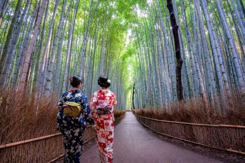 Two people walking down a bamboo forest path. 1