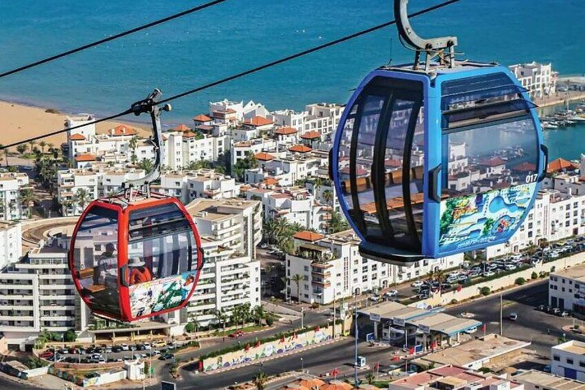 Twee kabelbanen boven een kustplaats met gebouwen en een strand. 1