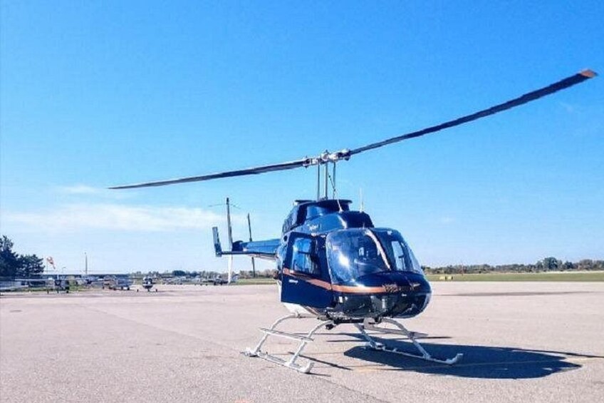 A blue helicopter on a tarmac with a clear sky in the background. 2