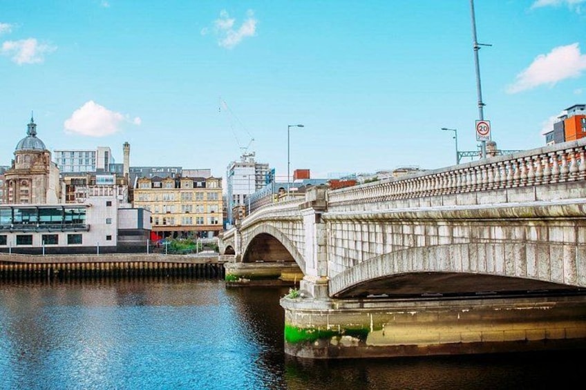 A stone bridge over a river with buildings and a dome in the background. 5