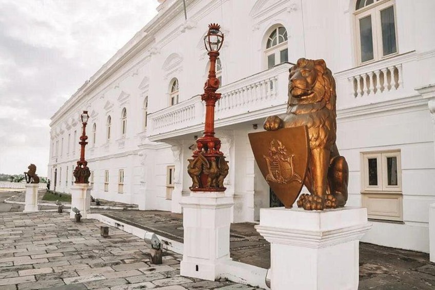 Un edificio blanco con columnas y estatuas, incluyendo un león dorado. 4