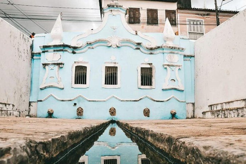 Un edificio azul con detalles ornamentales y un estrecho canal de agua en primer plano. 3
