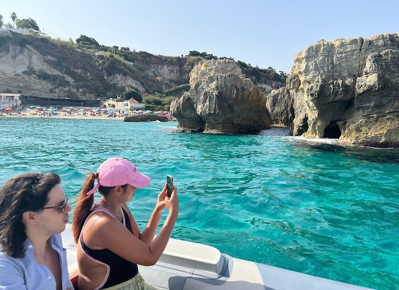 A boat on clear turquoise water with rocky cliffs and a beach in the background. 3