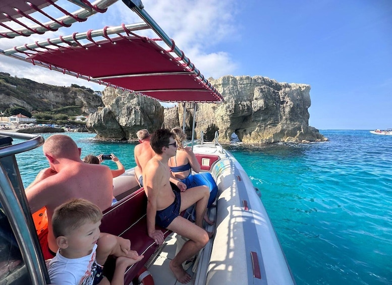 A boat with passengers enjoying a sunny day at a coastal location with rocky cliffs. 5