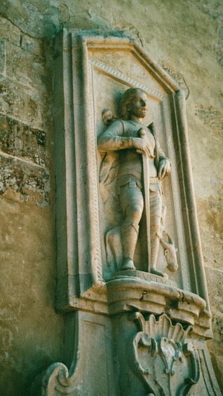 A stone relief of a figure holding a staff, with the inscription 'CEVSTAC' on the base. 4