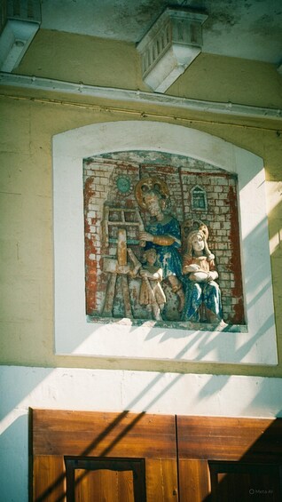A fresco mural on a wall with a wooden door below. 2