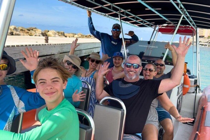 A group of people on a boat with a rocky shoreline in the background. 1