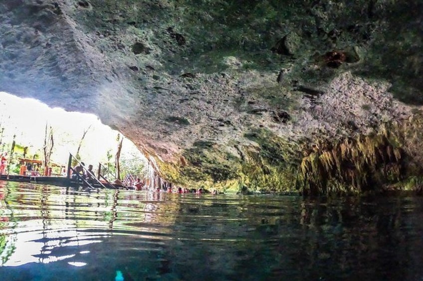 A cave with water reflecting the interior and people swimming. 3