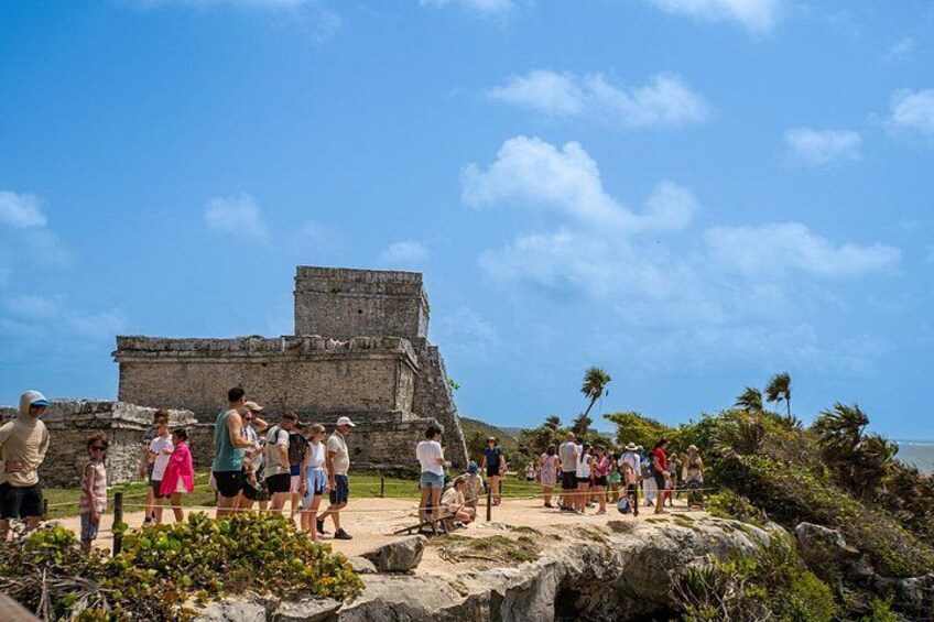 A group of people at a historical site with ancient ruins and a clear blue sky. 2