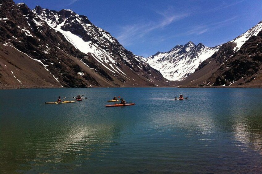 A calm lake surrounded by mountains with kayakers. 1