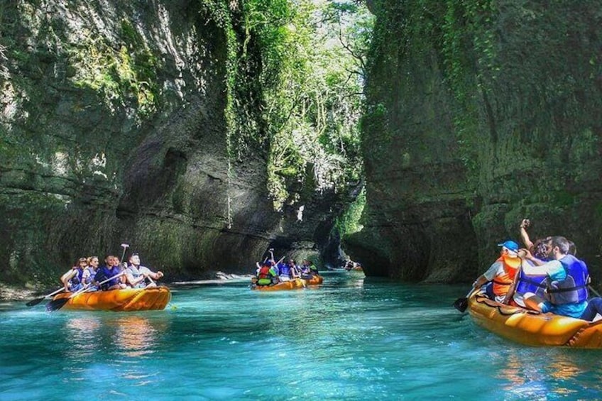 Des personnes pratiquent le rafting sur une rivière bordée de falaises rocheuses. 1
