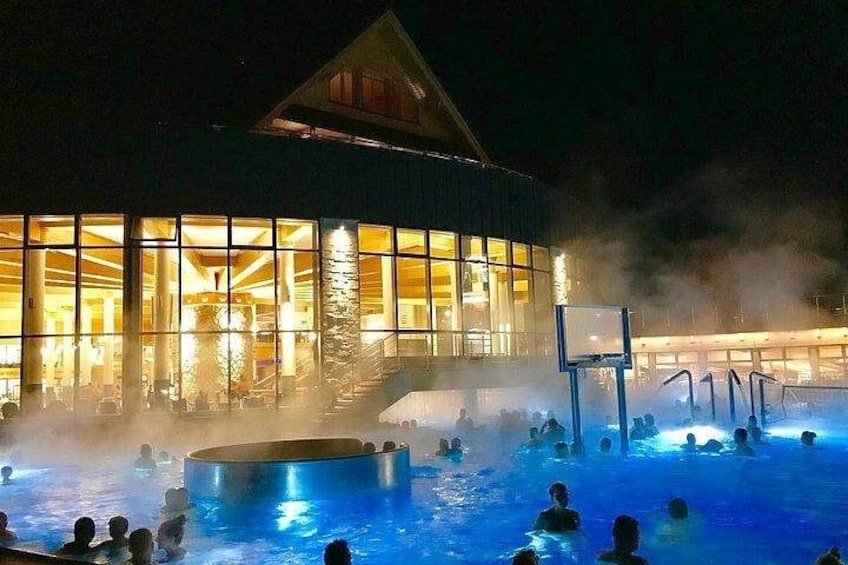 Un edificio con amplios ventanales y un área de piscina con gente. 2
