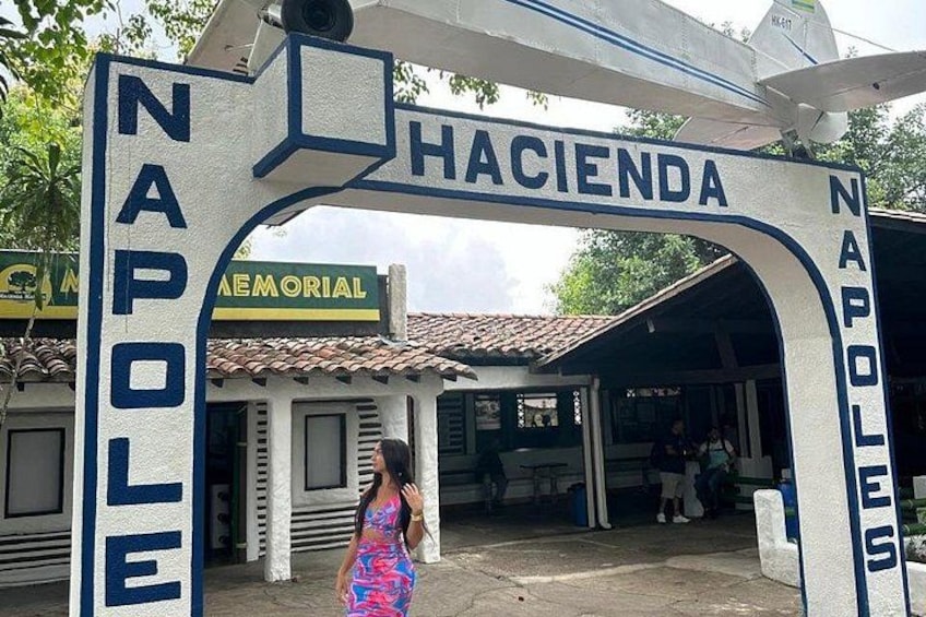 A sign with 'NAPOLE' and 'HACIENDA' written on it, with a building in the background. 1
