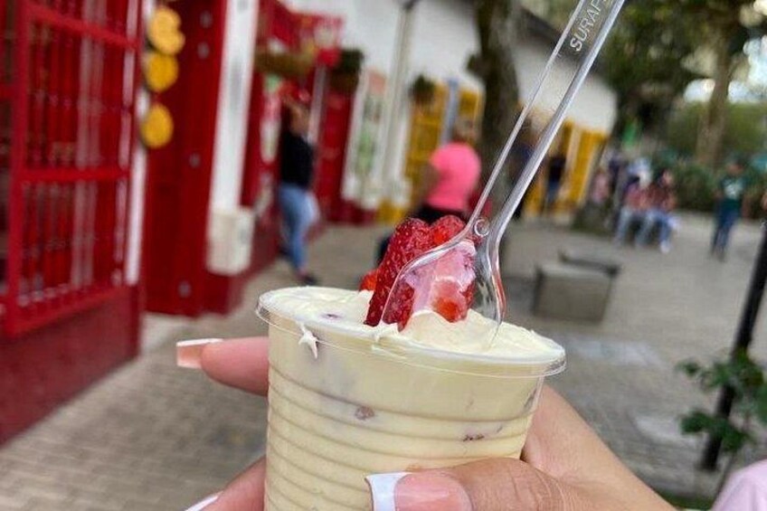 Eine Hand hält eine Tasse Dessert mit einer Erdbeere obenauf. 4