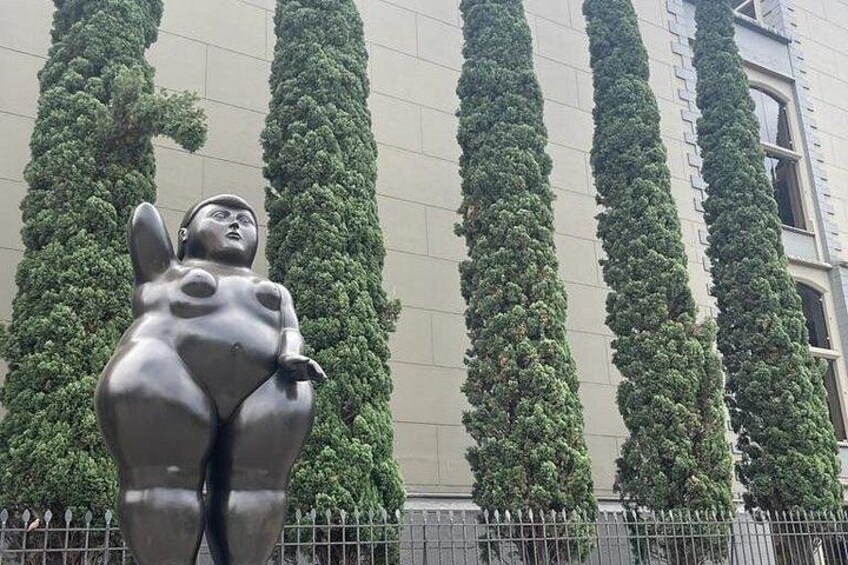 Eine Statue einer Frau mit großer Brust, umgeben von hoch aufragenden, grünen Bäumen. 5