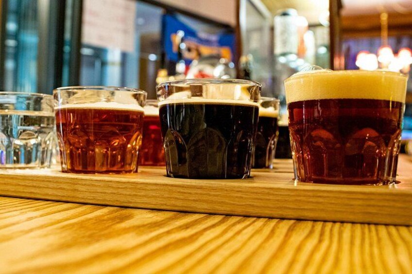 A wooden bar counter with various glasses of beer. 4