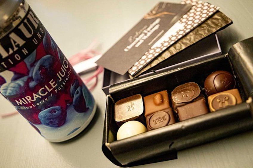 A can of Miracle Juice, a box of chocolates, and a chocolate bar on a table. 3