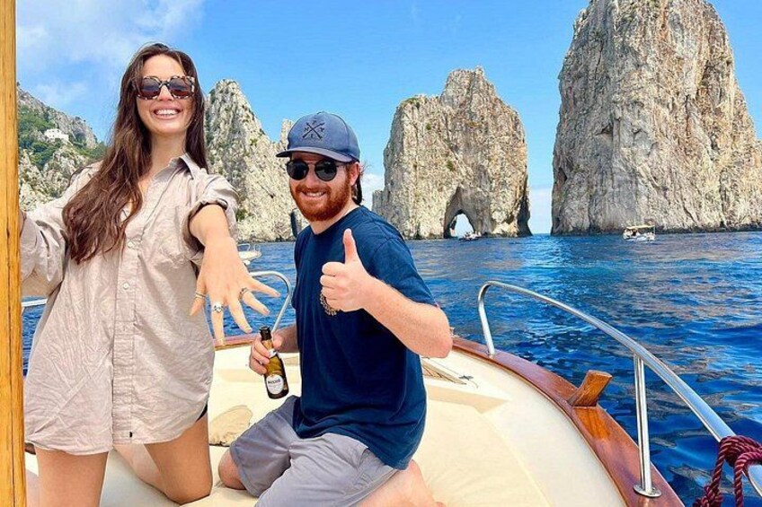 Un bateau avec deux personnes à bord, des falaises rocheuses et une eau d’un bleu cristallin. 1