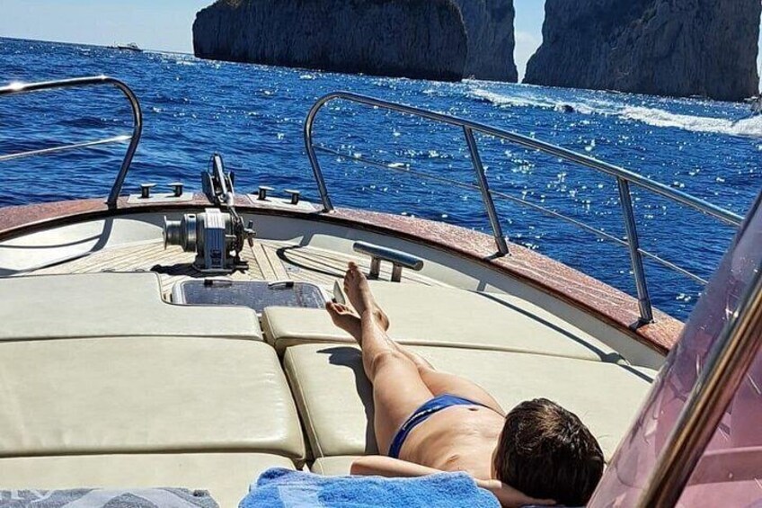 Une personne allongée sur le pont d’un bateau, avec vue sur la mer et les falaises rocheuses. 5