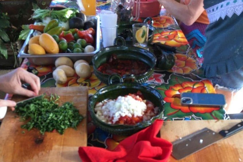 A table with various food items, including a cutting board with chopped greens, a bowl of tomatoes, and a plate of vegetables. 2