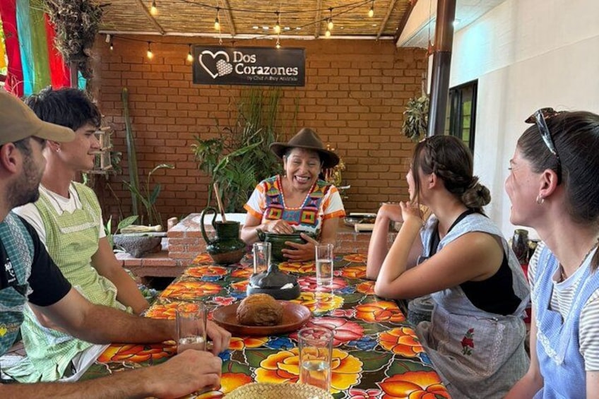 A group of people dining at a restaurant with a colorful tablecloth and a brick wall background. 3